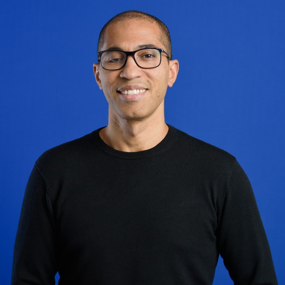 Portrait of Salime Nassur smiling, on a blue background