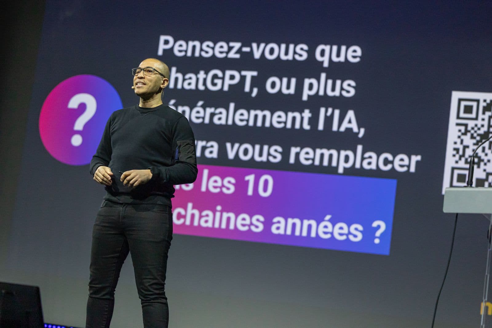 Salime Nassur giving a keynote in front of a screen asking whether AI will replace the audience within ten years